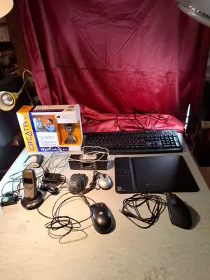 Gesamtansicht aller Geräte: Tastatur, Maus, Monitor, Telefon, Netzteile und Kabel auf Tisch