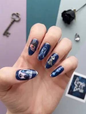 Hand mit dunkelblau bemalten Nägeln, Motive mit weißen Figuren und Schrift