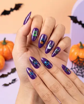 Hand mit lila Nageldesign, Stitch-Motive auf glitzerndem Untergrund, Halloween-Deko im Hintergrund