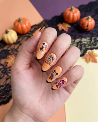 Hand mit bemalten Nägeln in Orange mit Halloween-Motiven wie Kürbissen und Spinnen