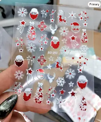 Nagelsticker-Bogen mit weihnachtlichen 3D-Motiven in Rot, Weiß und Silber, in der Hand gehalten