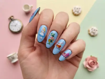 Hand mit blauem Nagellack und Alice-im-Wunderland-Motiven auf den Nägeln