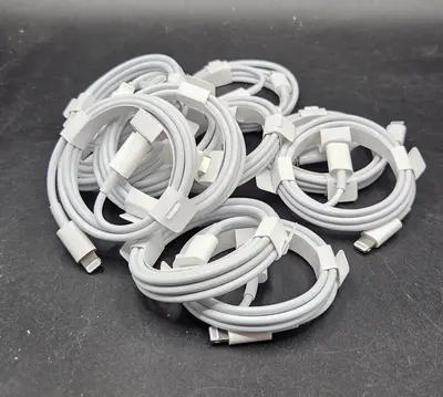 Mehrere aufgerollte Lightning-zu-USB-C-Kabel in Weiß auf dunklem Untergrund