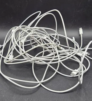 Mehrere weiße Lightning-auf-USB-C-Kabel aufgewickelt auf grauem Untergrund