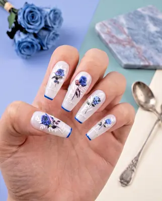 Nagellack-Design mit blauen Blumenmotiven auf naturfarbenem Untergrund, aufgetragen auf einer Hand