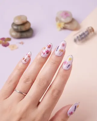 Nagellack-Design mit bunten Blüten und Schmetterlingen auf den Fingernägeln einer Hand