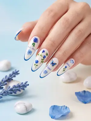 Hand mit Nagelstickern: längliche weiße Nägel mit blauen 3D-Blüten und feinen Linien verziert