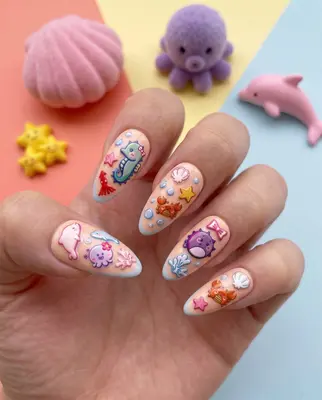 Hand mit bunten Nägeln, bemalt mit Meerestieren wie Fischen, Quallen und Seesternen in Pastellfarben